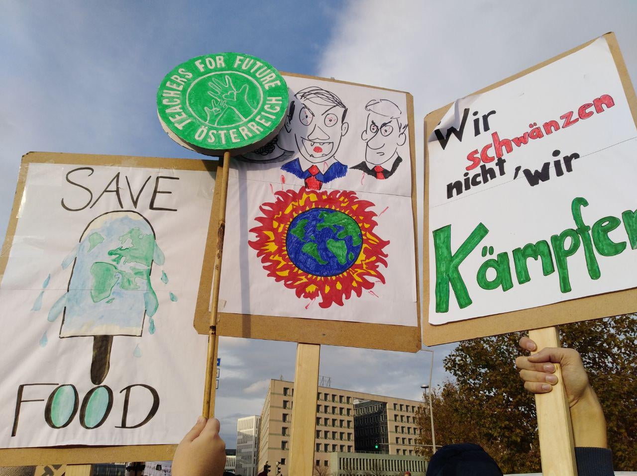 Mehrere Demo-Schilder werden in die Luft gehalten