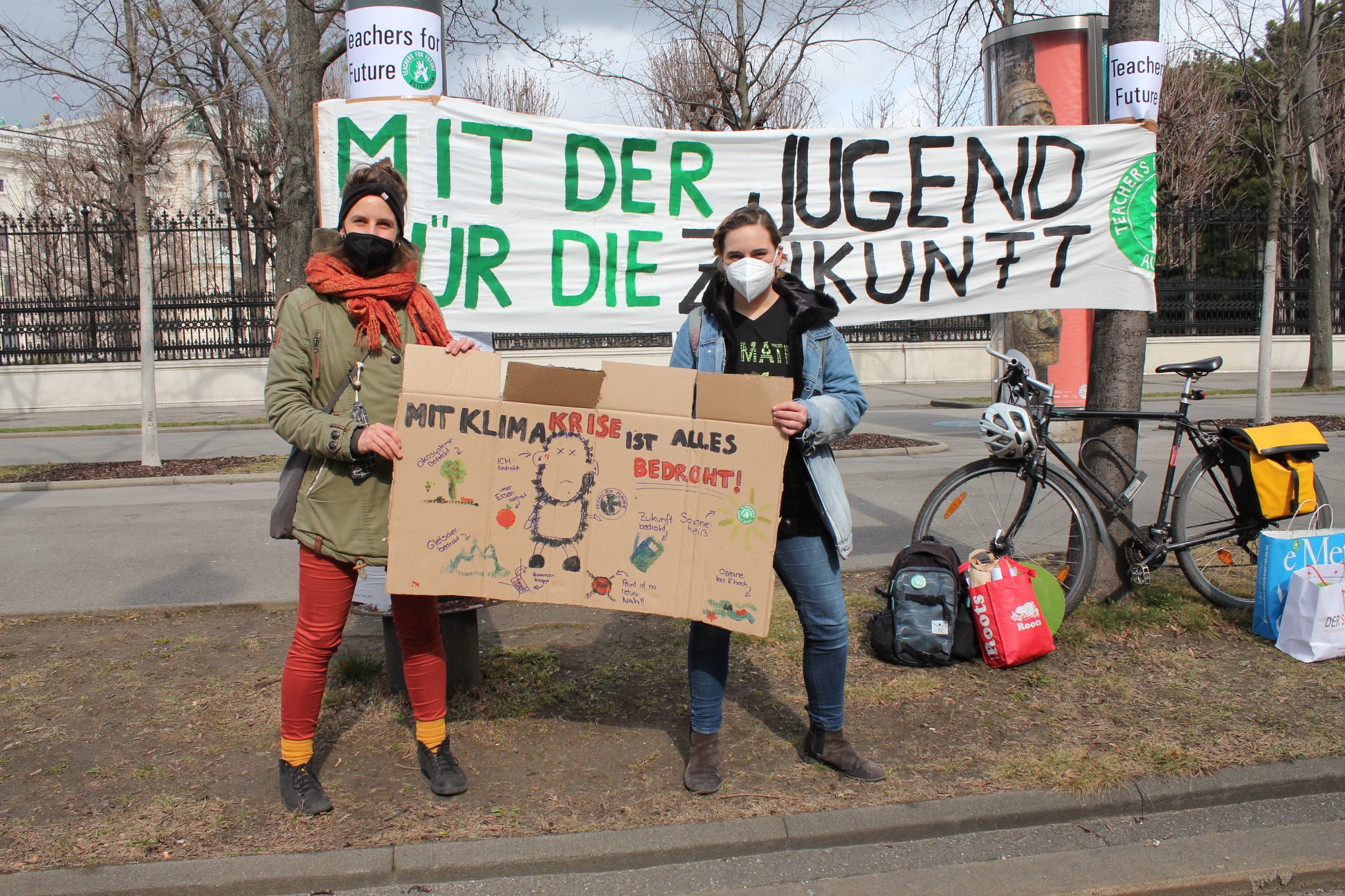 Teachers For Future präsentieren Demo-Schild vor Banner „Mit der Jugend für die Zukunft
