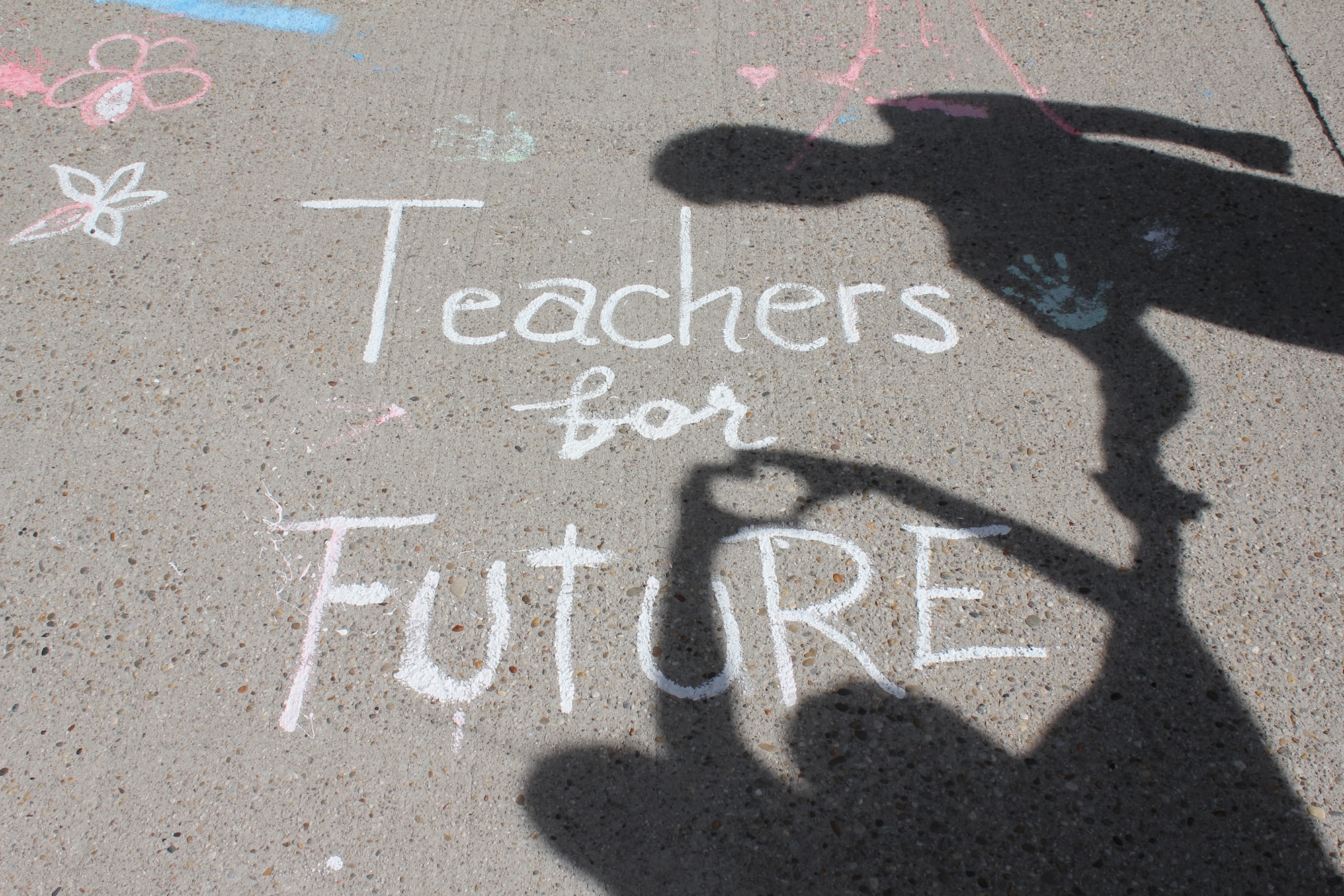 Hände werfen ein Schattenherz auf den Schriftzug "Teachers for Future" am Asphaltboden