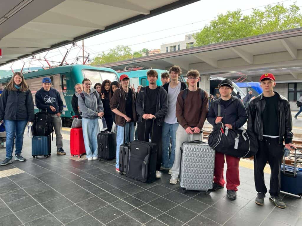 Schüler:innen des BORG Neulengbach posieren auf dem Bahnsteig in einem italienischen Bahnhof.
