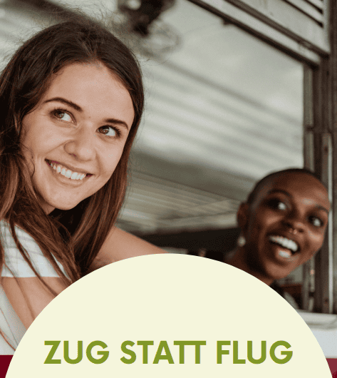Zwei Reisende blicken lachend aus einem offenen Zugfenster, darunter der Schriftzug "Zug statt Flug"