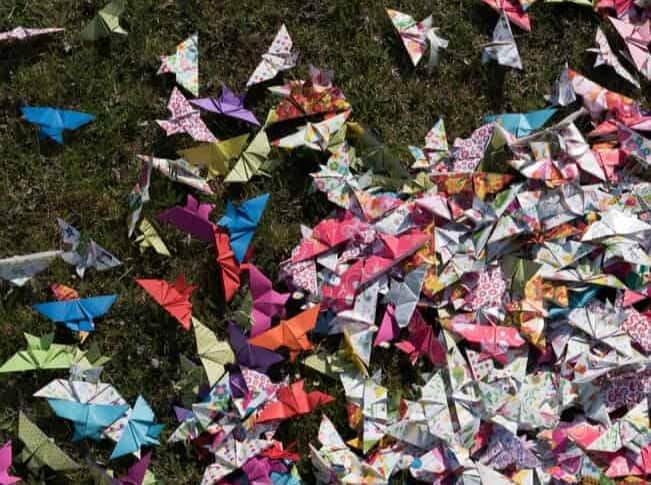 Papierschmetterlinge liegen im Gras und bilden einen Verband.